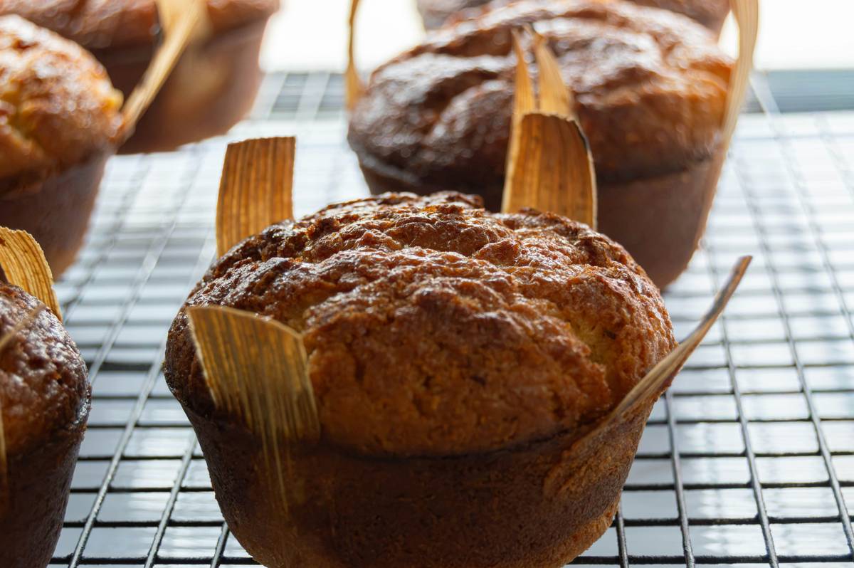 Golden brown muffins in paper liners on a black wire cooling rack